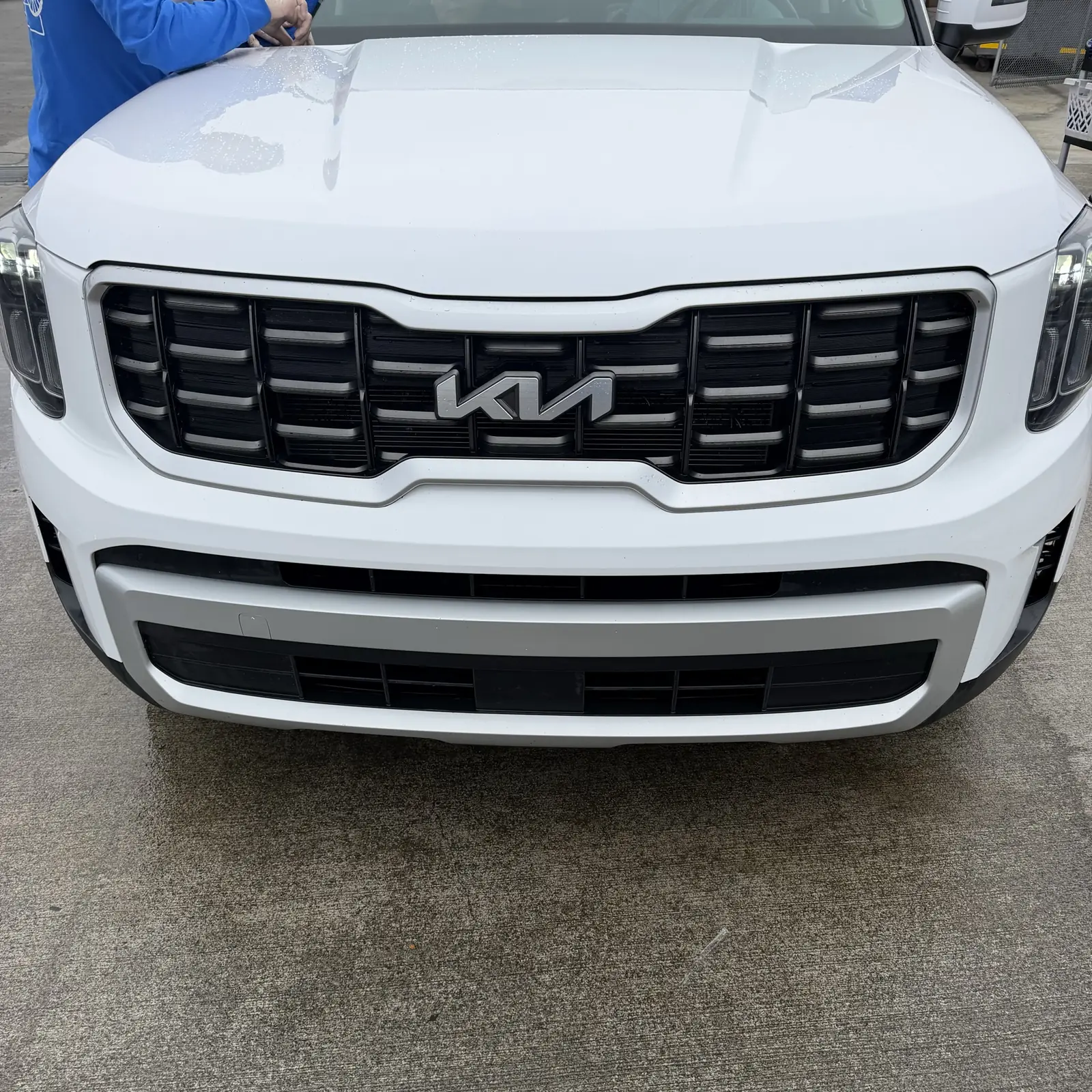 After: the same white Kia with a clean grille and bumper