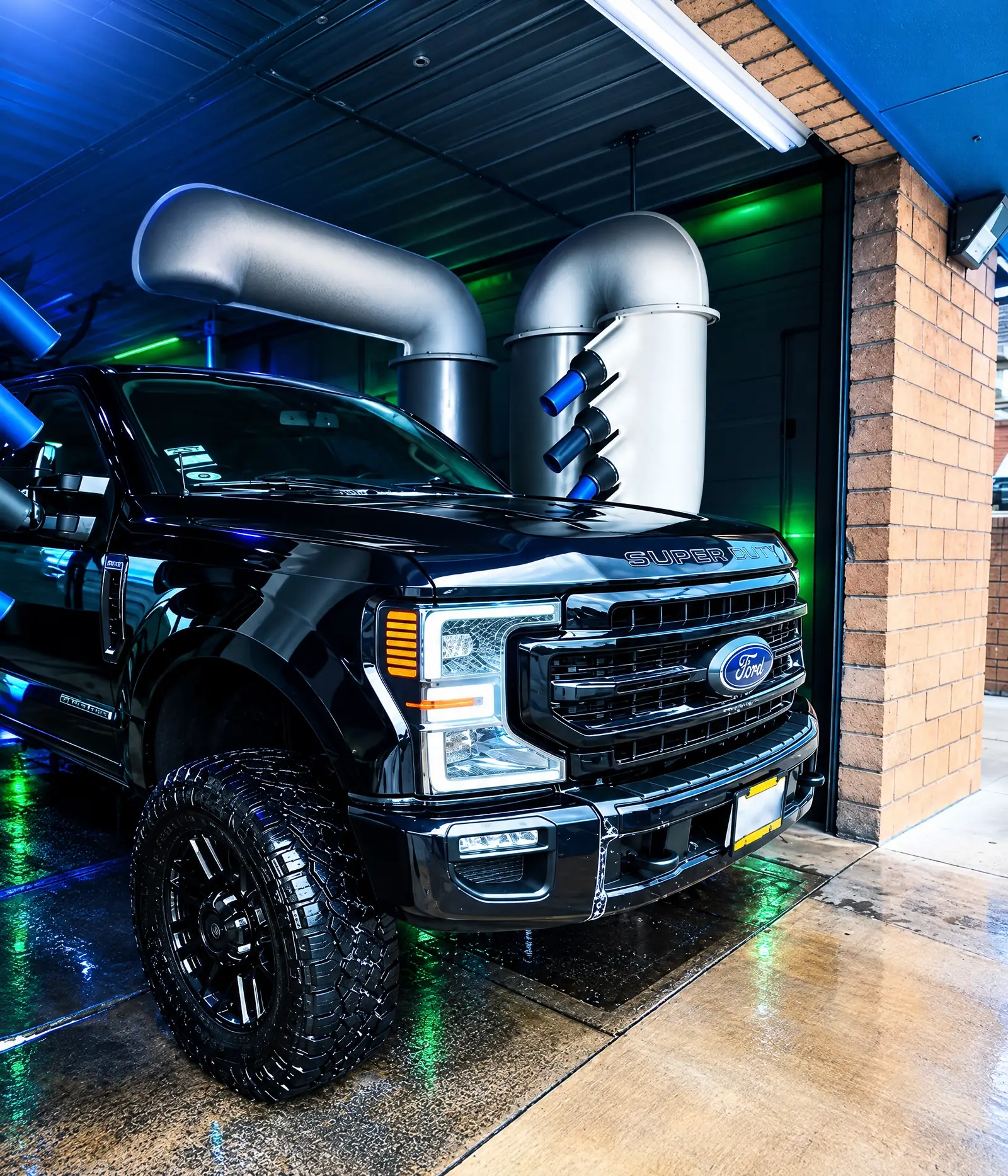 A lifted black Ford Super Duty rolling out of the tunnel under the dryers at Zenith Car Wash
