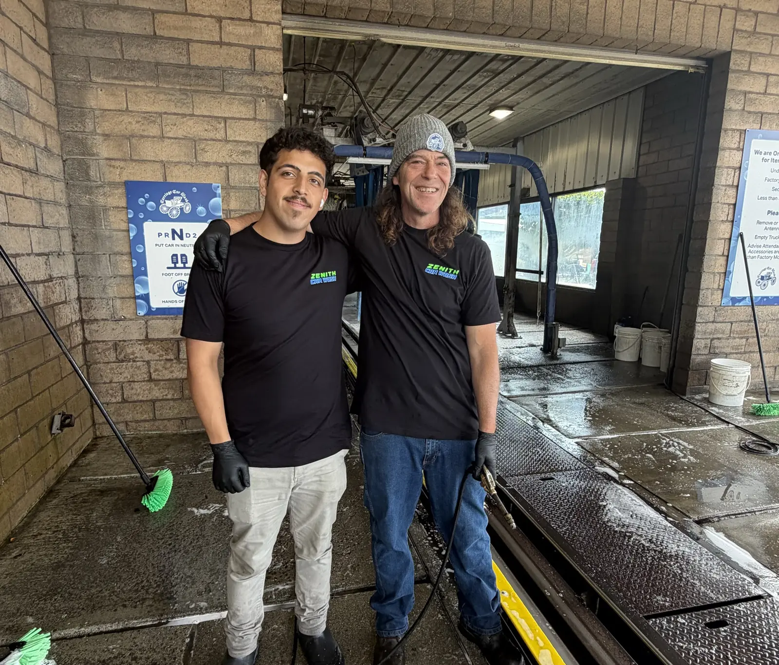 Two Zenith Car Wash crew members standing at the tunnel entrance