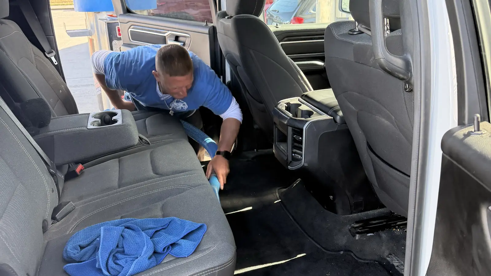 A Zenith crew member wiping down the back seat of a truck during an interior clean